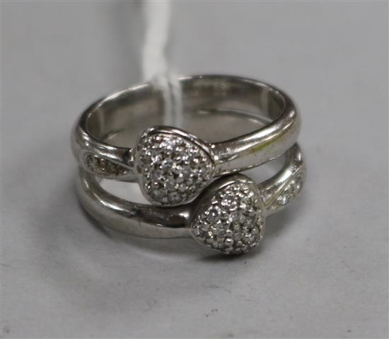 A white metal and diamond set twin hearts dress ring, size J.